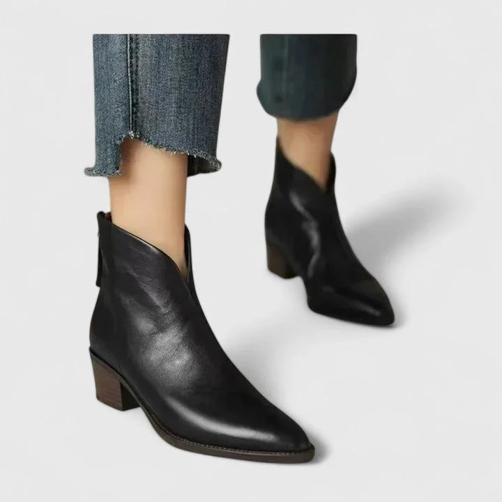 Pair of black faux leather ankle boots with V-cut shaft, worn