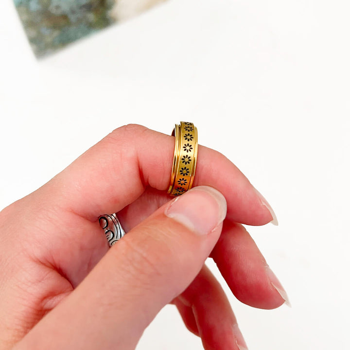 Gold spinner ring with daisy engraving worn on woman&