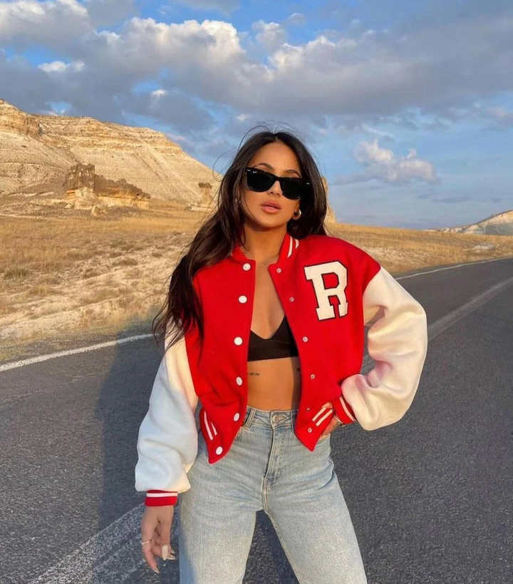Woman wearing red and white oversized varsity bomber jacket on road | Grace Aura