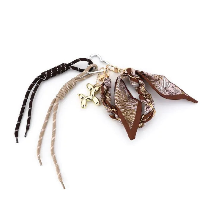 Brown braided leather bag charm with gold balloon dog pendant and tassels | Grace Aura