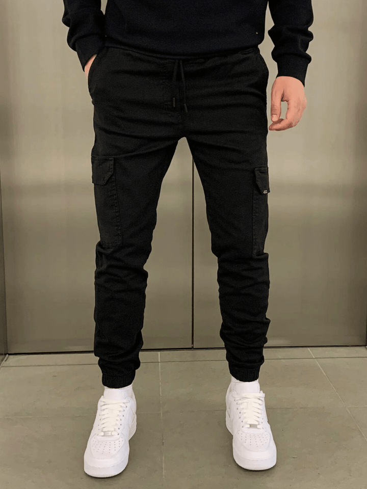 Black cargo joggers with drawstring worn by man, paired with white sneakers | Grace Aura