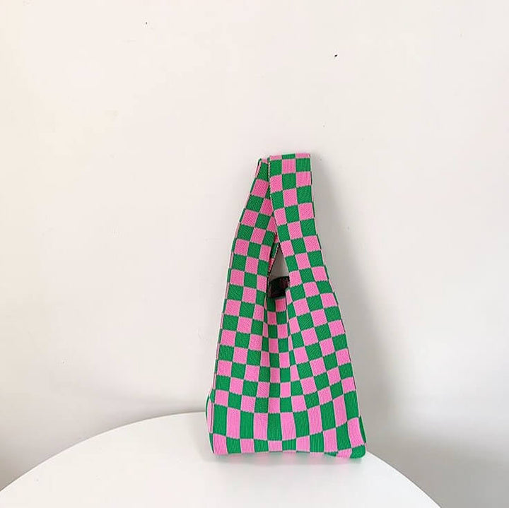 Green and pink checkerboard knit tote bag standing upright on chair | Grace Aura