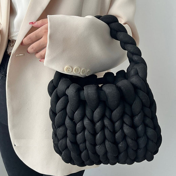 Black chunky knit braided handbag held by woman wearing beige blazer | Grace Aura