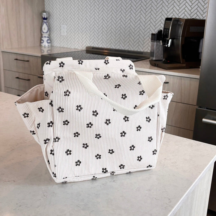White corduroy lunch tote with black floral print, standing open on countertop | Grace Aura