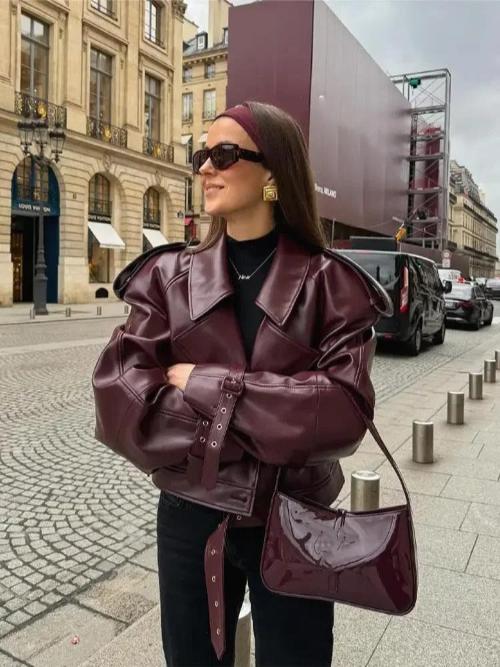 Woman wearing burgundy faux leather belted jacket with matching patent shoulder bag outdoors | Grace Aura