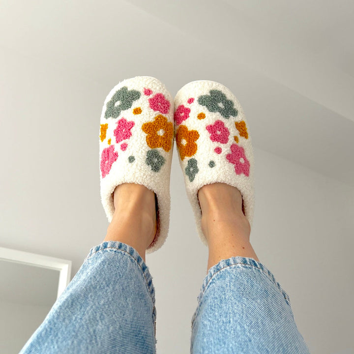 White plush slippers with pink orange floral embroidery, worn on feet | Grace Aura