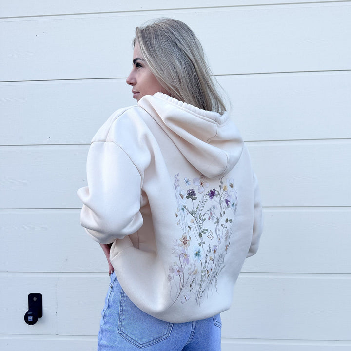 Cream hoodie with floral back print worn by woman outdoors | Grace Aura