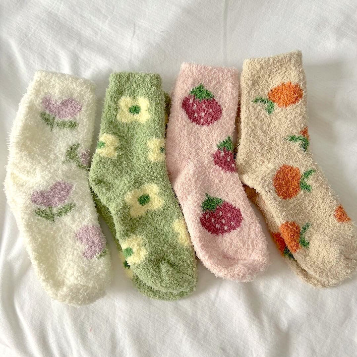Four fuzzy socks laid flat with floral and fruit patterns in pastel colors | Grace Aura