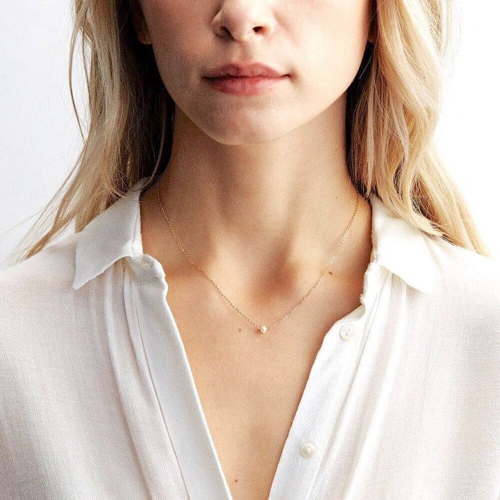 Gold pearl pendant necklace worn by woman in white blouse | Grace Aura