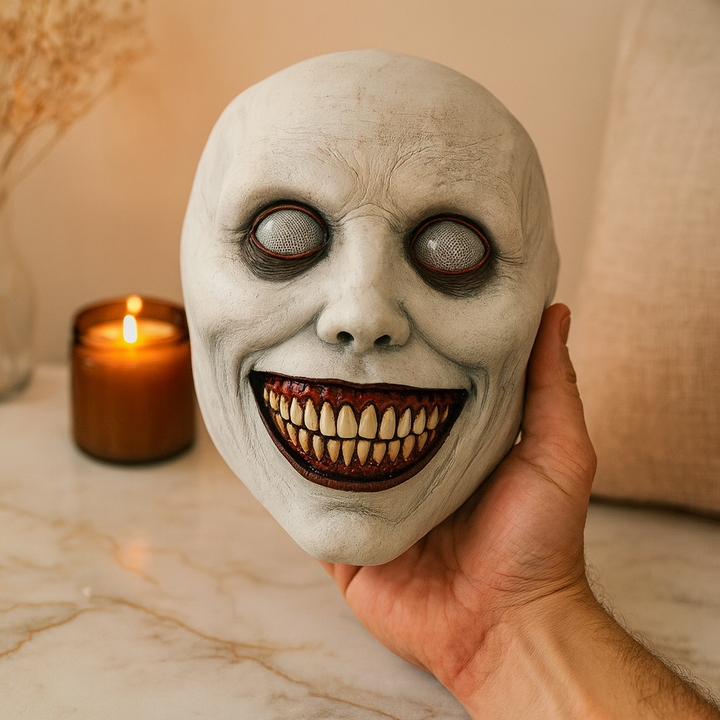 Hand holding white latex horror mask with mesh eyes and teeth | Grace Aura