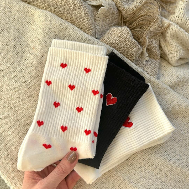 Hand holding folded white and black heart print cotton socks | Grace Aura