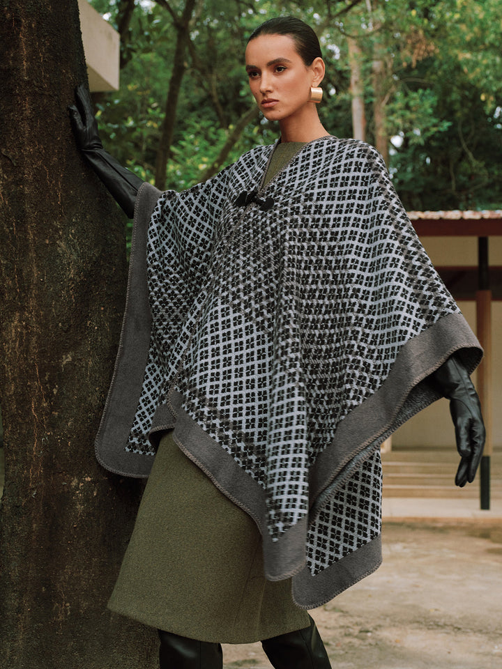 Woman wearing grey houndstooth knitted poncho with olive skirt outdoors | Grace Aura