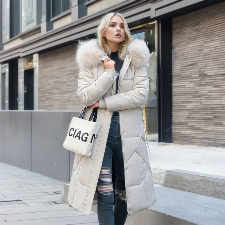 Beige quilted long puffer jacket with fur hood, worn by woman outdoors | Grace Aura