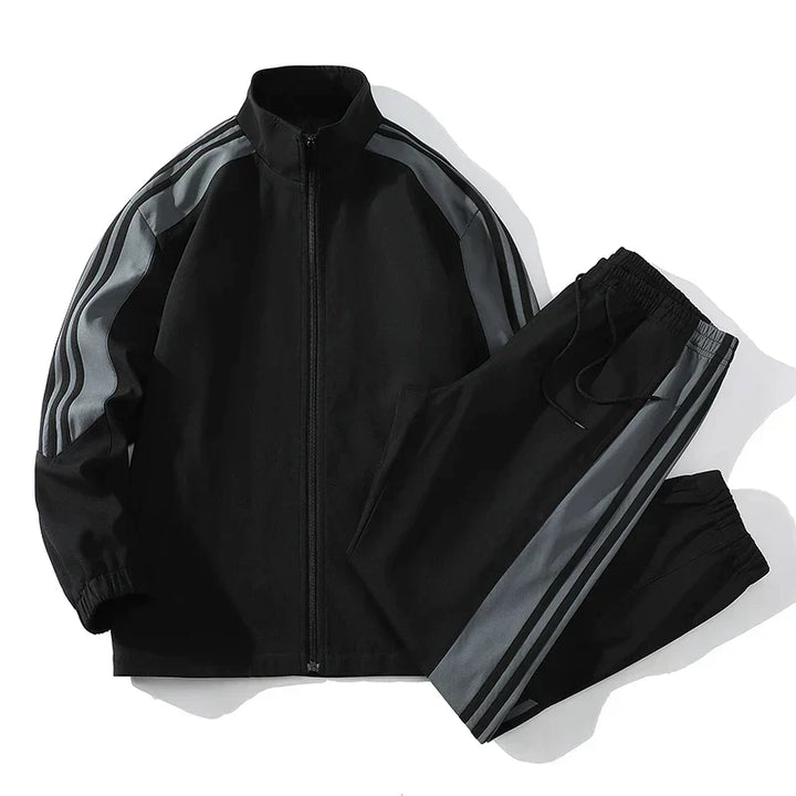 Black tracksuit with gray stripes, zip-up jacket and jogger pants, flat lay | Grace Aura