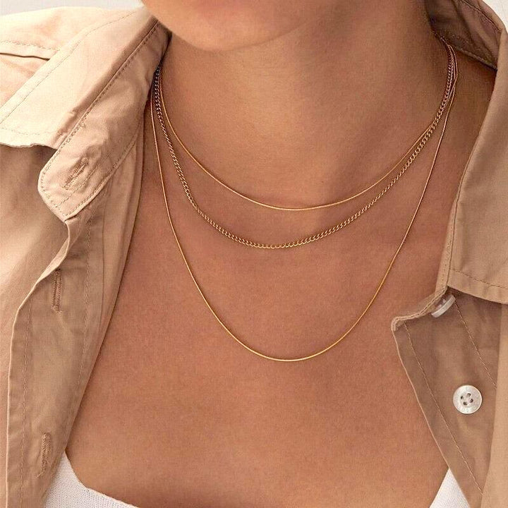 Layered thin gold chain necklaces worn by woman in beige jacket | Grace Aura