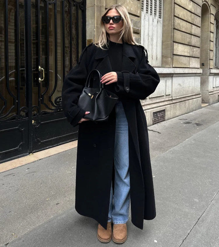 Woman wearing black oversized belted trench coat with blue jeans outdoors | Grace Aura