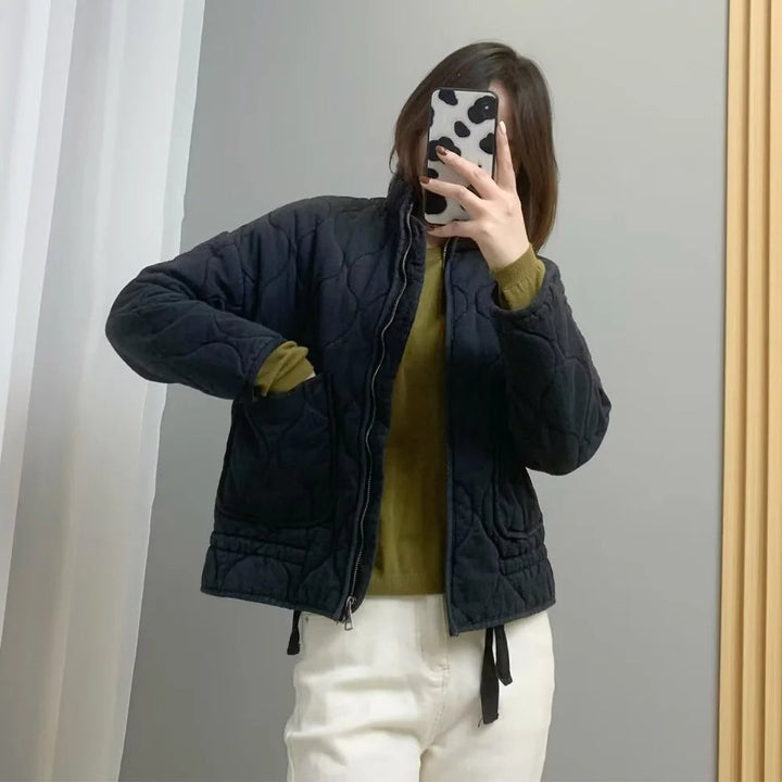 Black quilted oversized jacket worn by woman, olive sweater underneath, drawstring hem | Grace Aura