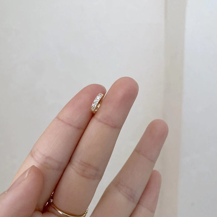 Gold pave huggie hoop earring held between fingers, worn demonstration | Grace Aura