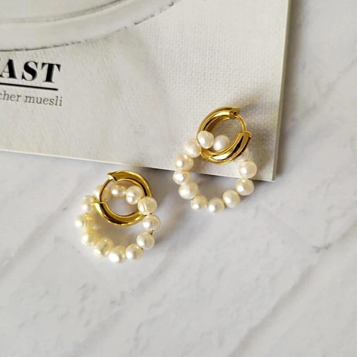 Gold hoop earrings with pearl beaded circles, laid flat on marble | Grace Aura
