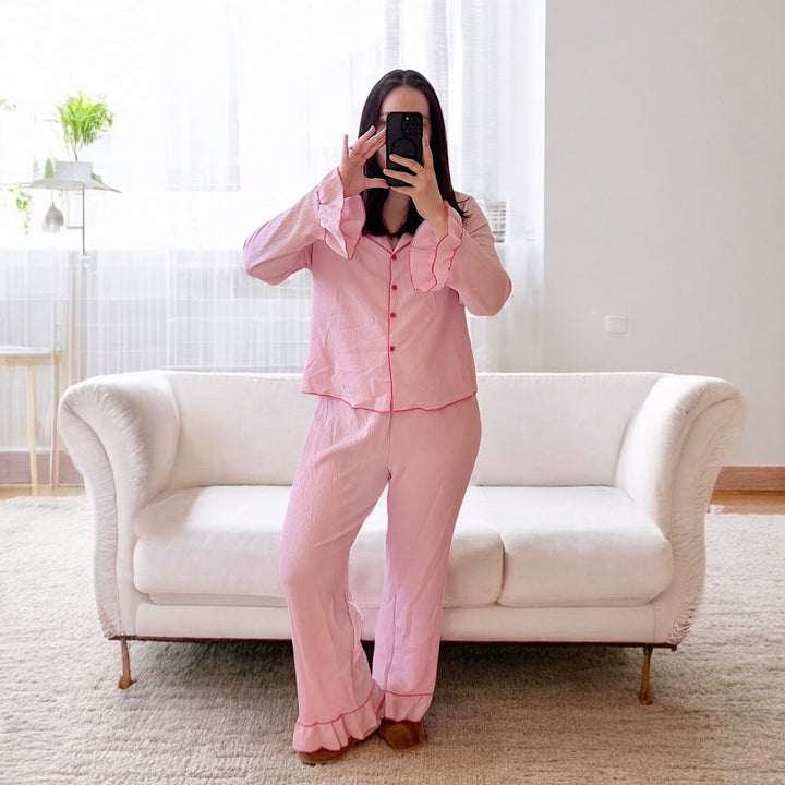 Woman wearing pink long-sleeve button-up pyjama set with pants, standing indoors | Grace Aura