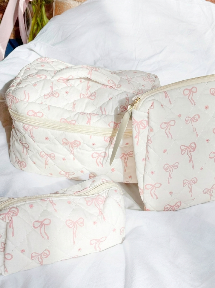 Three quilted cream makeup bags with pink bow print, laid flat | Grace Aura