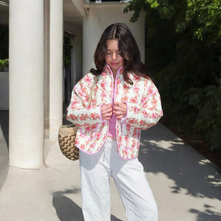 Woman wearing pink floral quilted jacket over pink top, white pants outdoors | Grace Aura