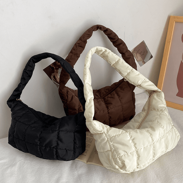 Black, brown, and cream quilted puffer shoulder bags displayed flat together | Grace Aura