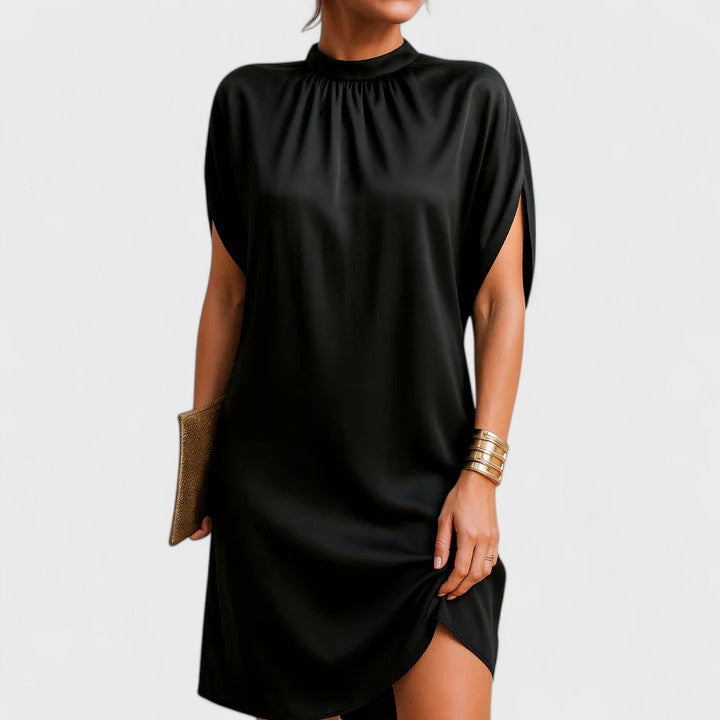 Black satin high-neck shift dress worn by woman with gold clutch | Grace Aura