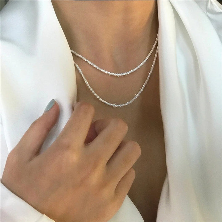 Layered silver chain necklace worn by woman in white blouse | Grace Aura