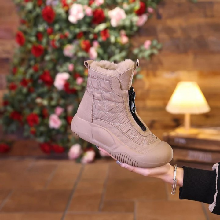 Beige quilted snow boot with fur trim, held by hand | Grace Aura