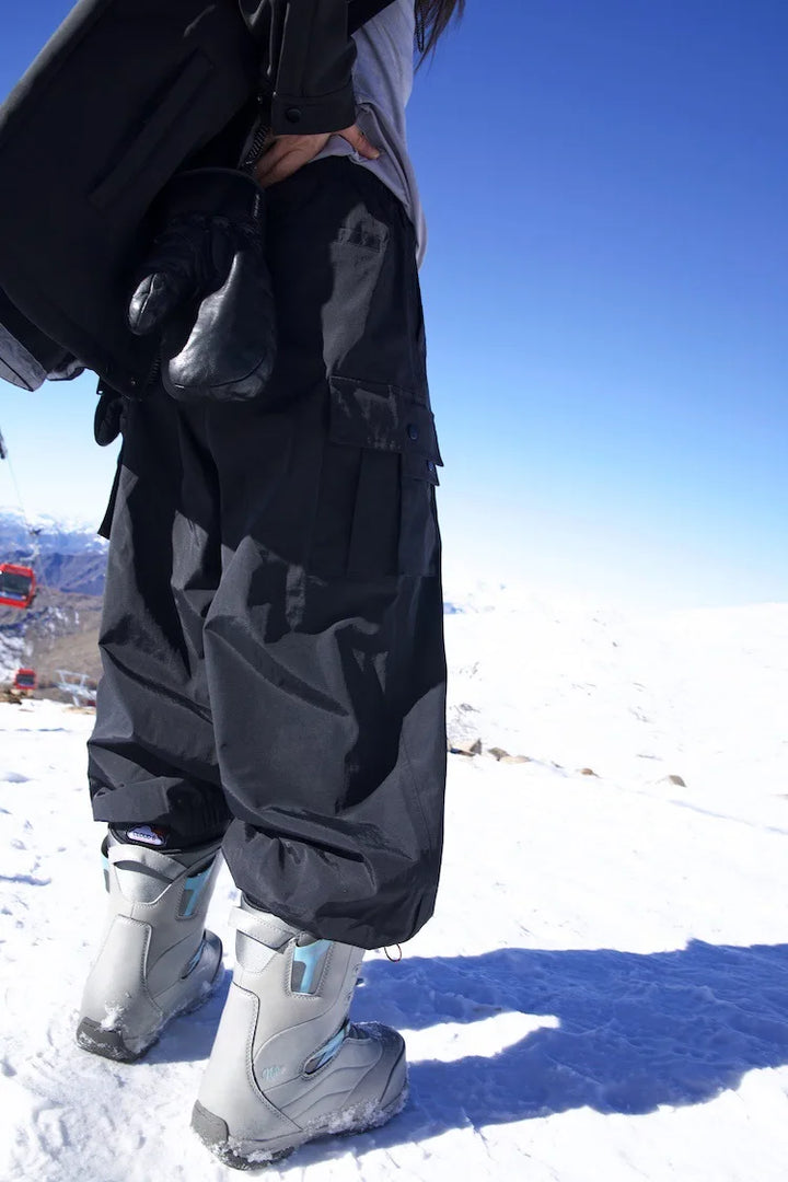 Black baggy cargo snow pants worn by person standing on snow | Grace Aura