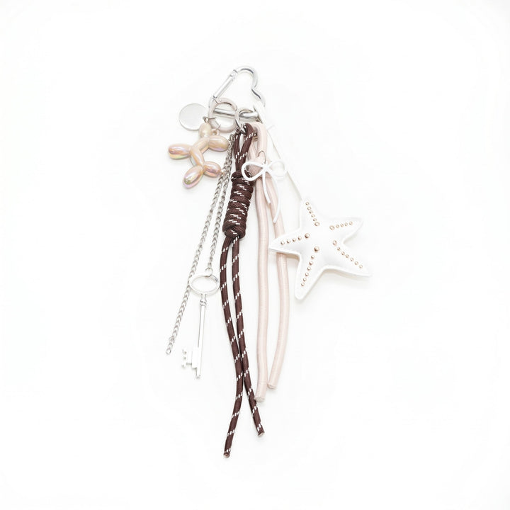 Silver starfish bag charm with brown cord tassels, flat lay display | Grace Aura