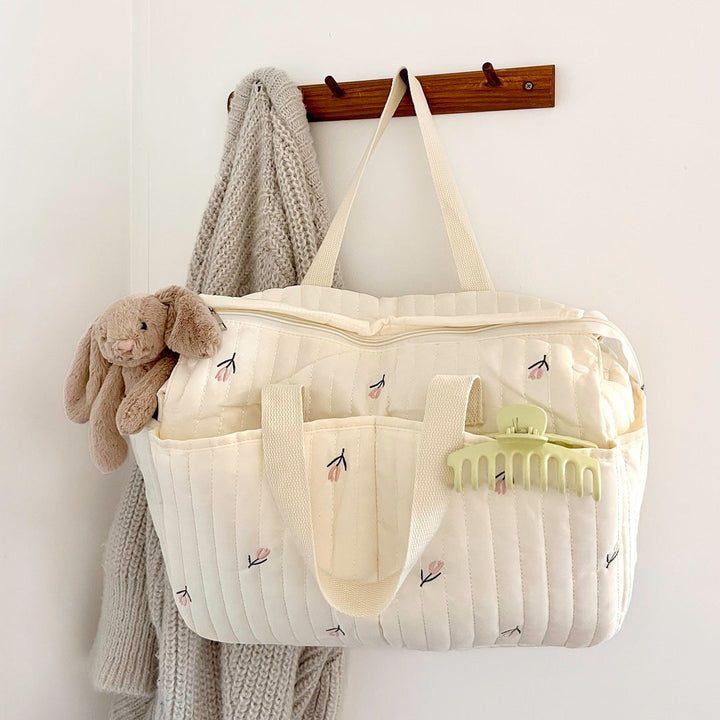 Cream quilted floral diaper tote bag hanging on wall hook | Grace Aura