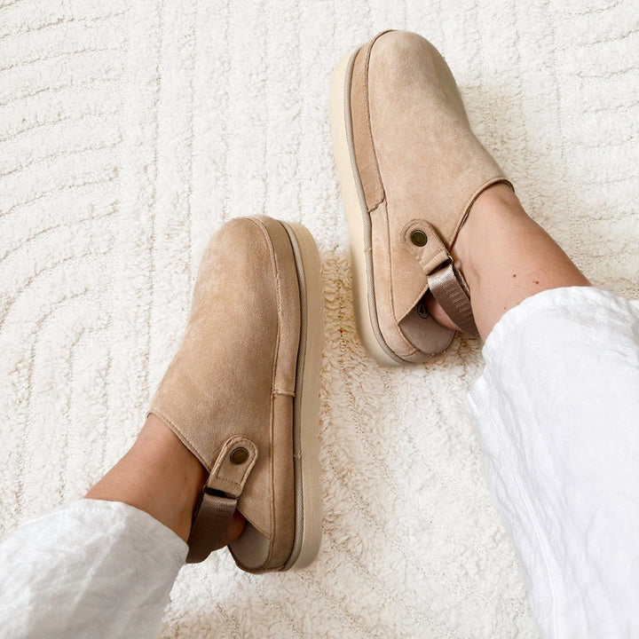 Beige suede platform clog mules worn on feet over textured cream rug | Grace Aura