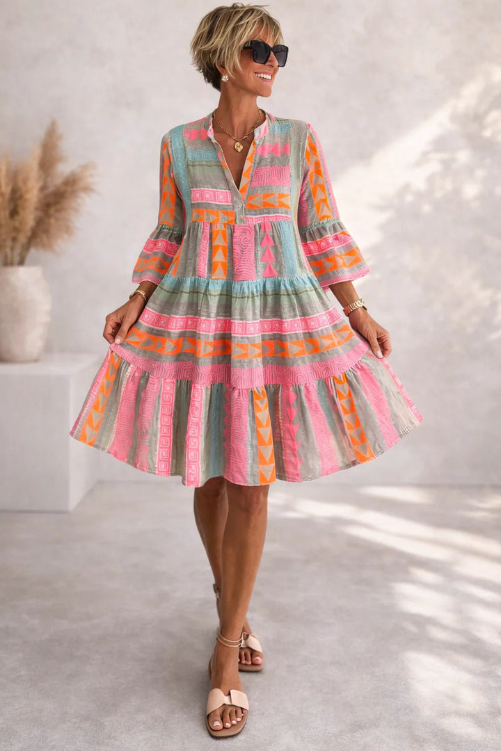Woman wearing colorful striped tiered dress with bell sleeves, standing outdoors | Grace Aura