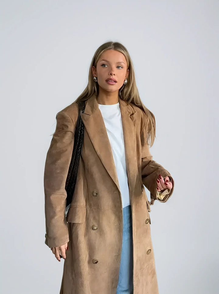 Woman wearing light brown suede double-breasted trench coat with black handbag | Grace Aura