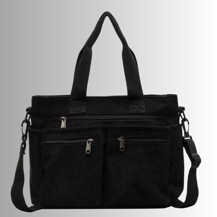Black canvas tote bag with front zip pockets and shoulder strap, flat lay | Grace Aura
