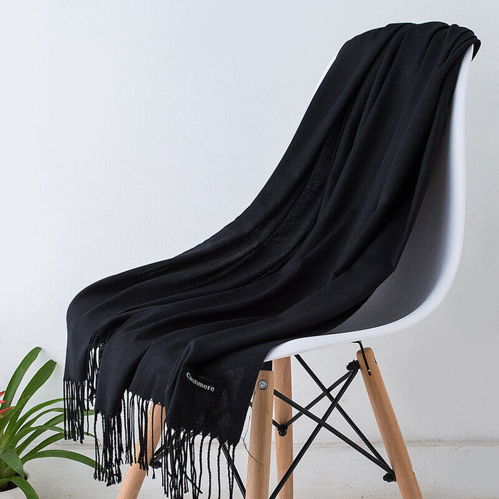 Black fringed cashmere scarf draped over white chair with wooden legs | Grace Aura