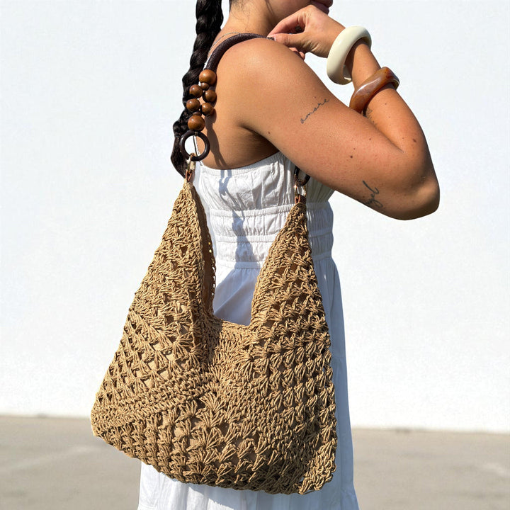 Woman wearing tan crochet tote bag with wooden bead shoulder straps outdoors | Grace Aura