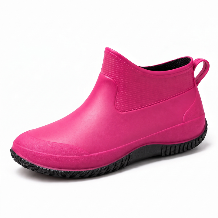 A magenta pink ankle height rain boot with a black treaded sole, shown in three quarter view on a plain white background.