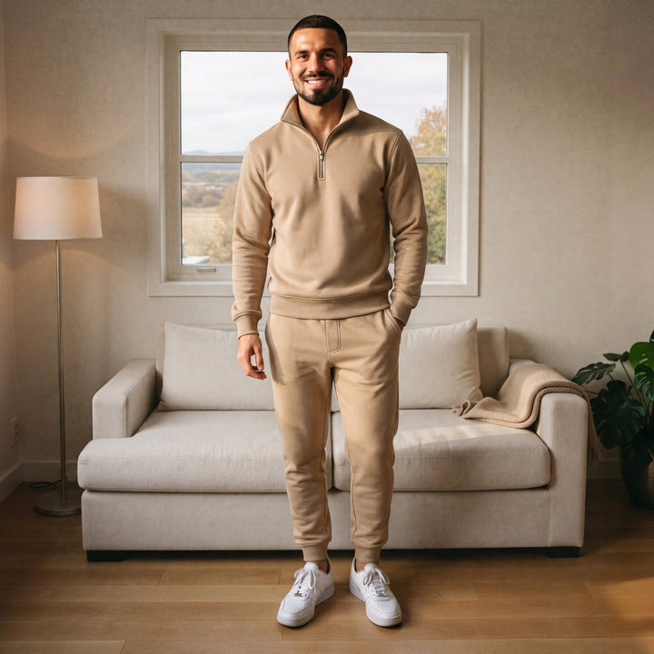 Man wearing beige half zip tracksuit with joggers, standing indoors | Grace Aura