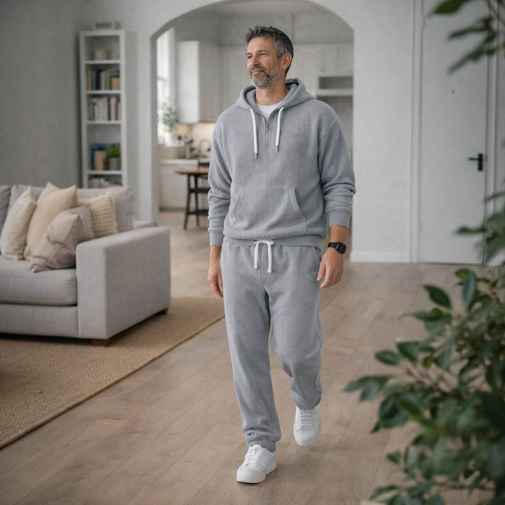 Man wearing grey hoodie and matching jogger sweatpants, walking indoors | Grace Aura