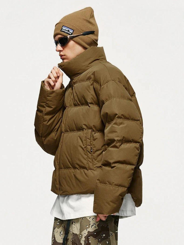 Man zipping up a brown cropped puffer jacket with a high collar