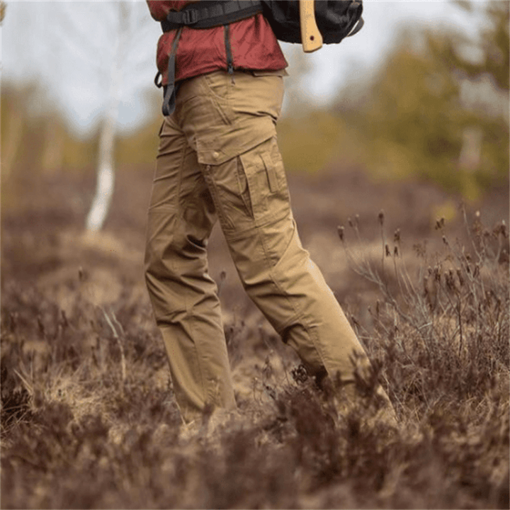 Man wearing khaki cargo trousers with pockets, walking through grassy field outdoors | Grace Aura