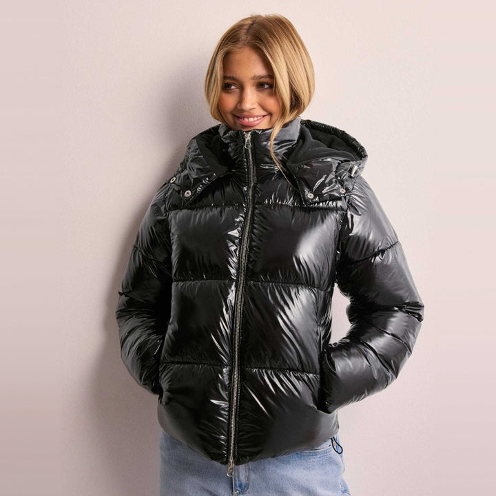Woman wearing black glossy quilted puffer jacket with hood, worn outfit | Grace Aura
