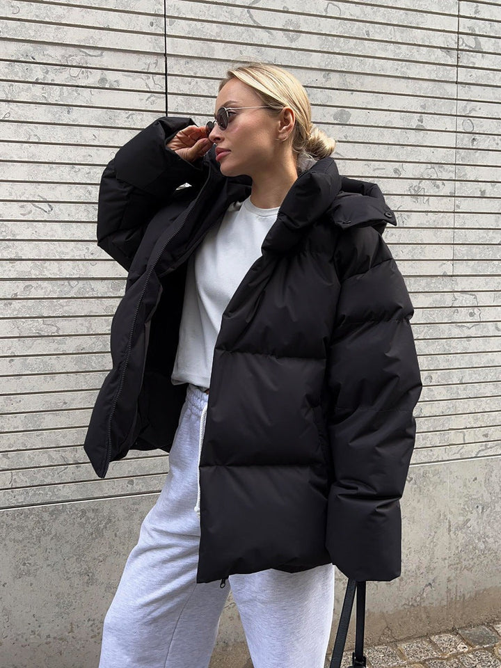 Black hooded puffer jacket for women, worn open with grey joggers