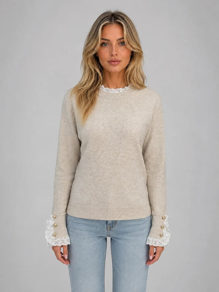 Front view of a beige knitted jumper with lace trim at the neck and cuffs