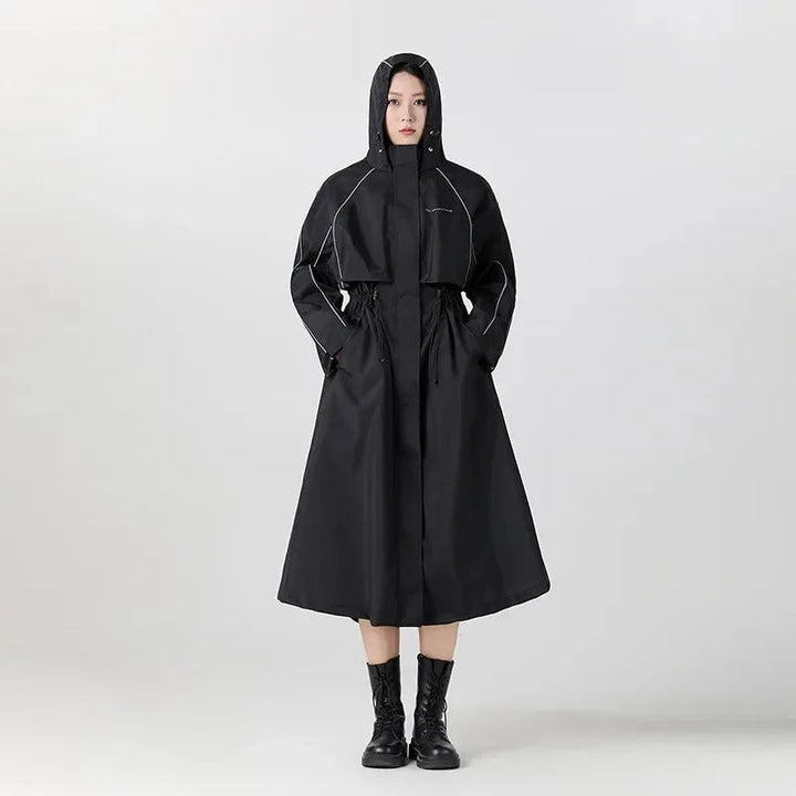 Woman wearing a long black oversized raincoat with the hood up