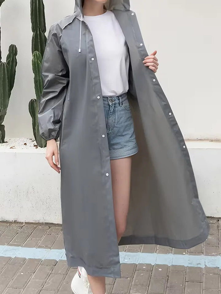Long grey hooded raincoat worn open over a white tee and denim shorts