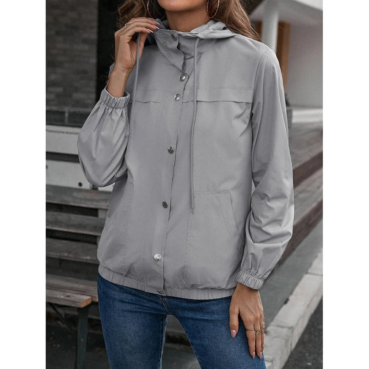 Grey hooded windbreaker with silver snap buttons, worn with jeans